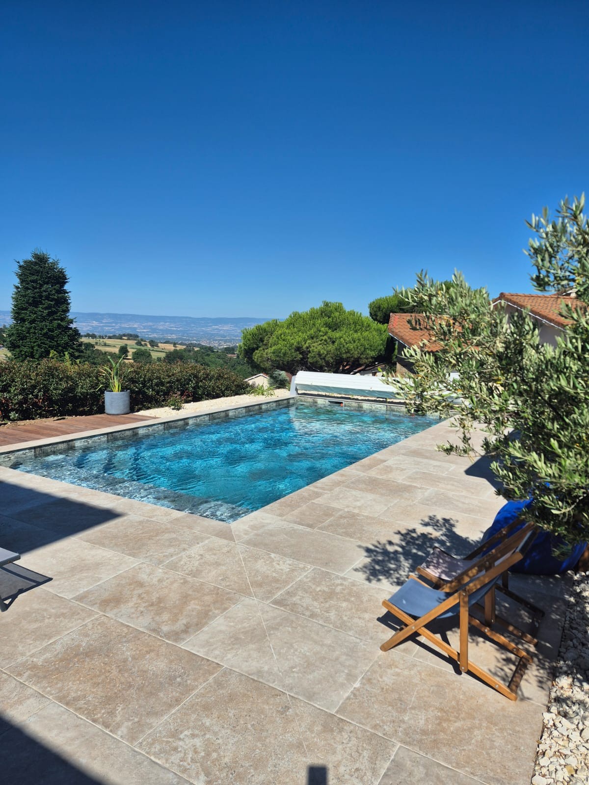 Piscine avec plage en travertin et vue dégagée sur la vallée