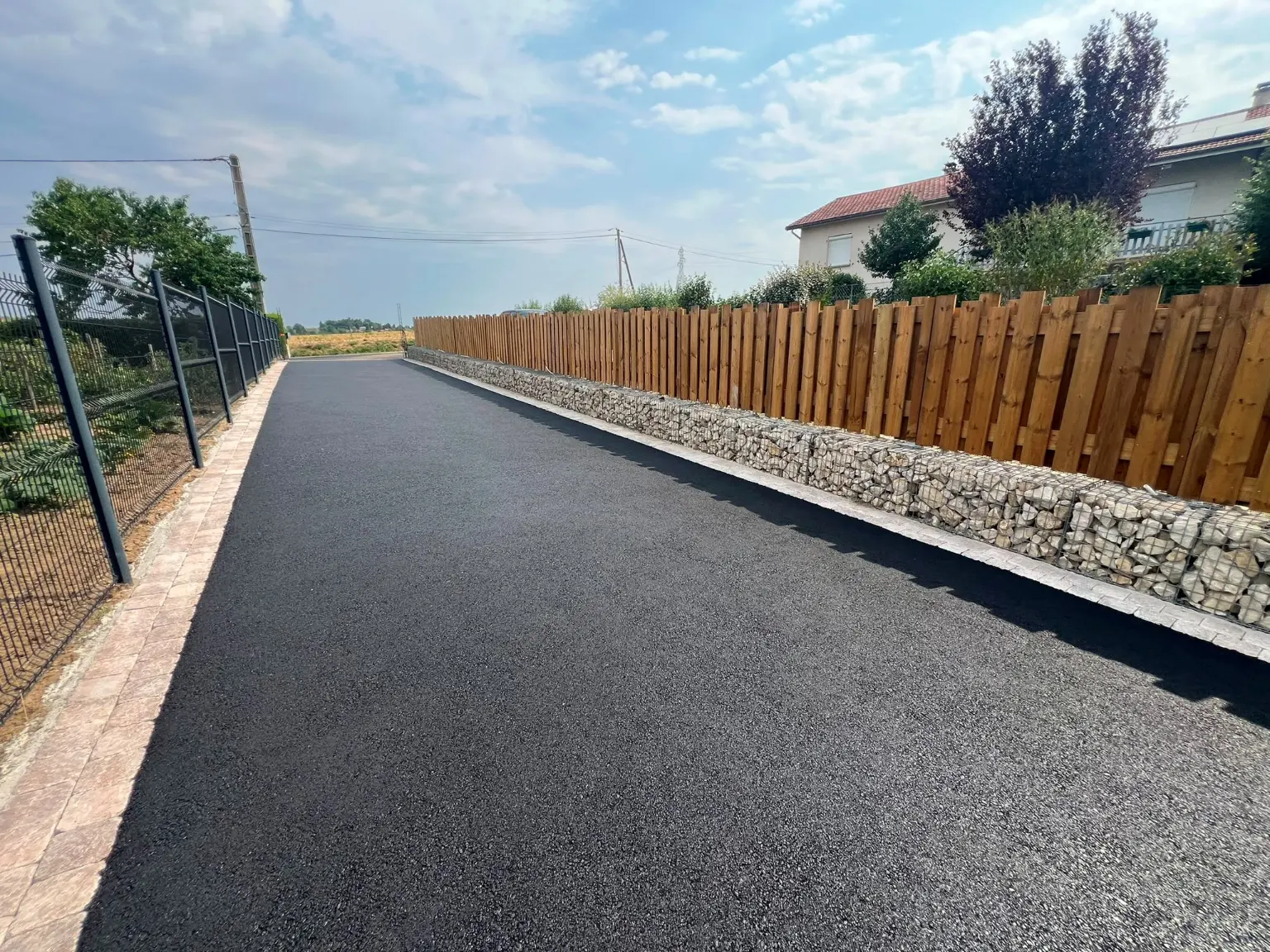 Allée en enrobé bordée d'un mur en gabion et d'une clôture en bois réalisée par AL Paysage